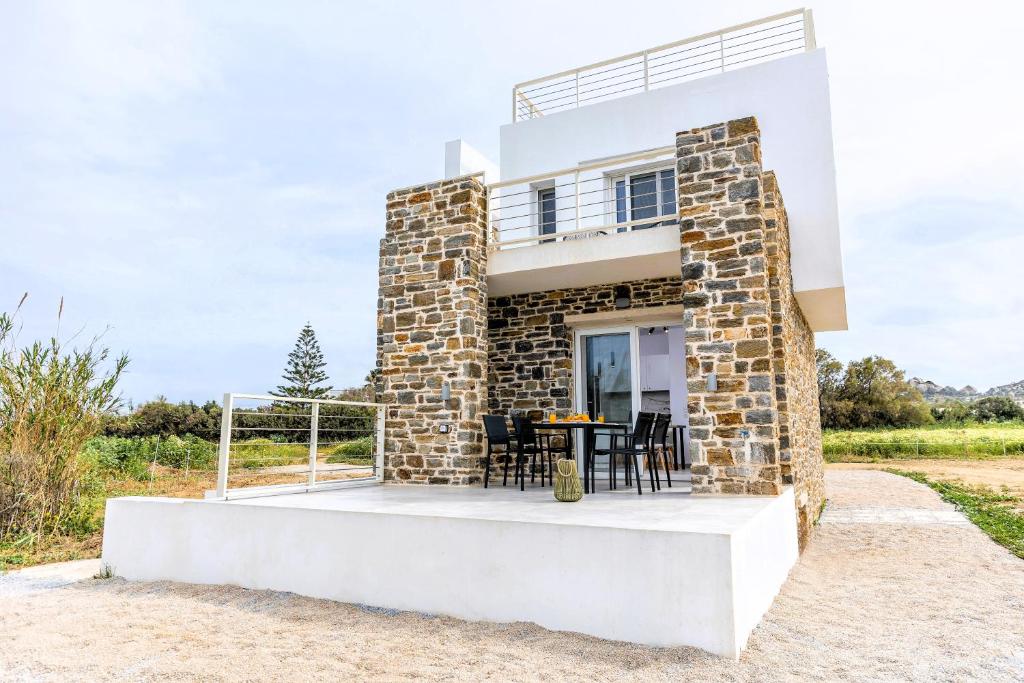 a house on the beach with a table and chairs at Naxos Cube Villa Panoramic Views Maisonette with Sea View 2 min walk to Plaka Beach in Plaka