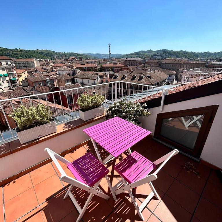 a pink table and two chairs on a balcony at La casetta sui tetti in Alba