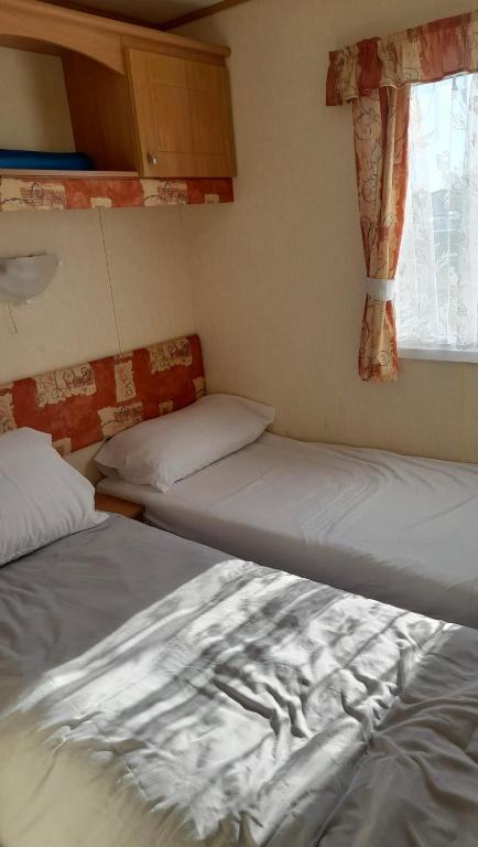 two beds in a small room with a window at The discovery whitehouse towyn in Kinmel Bay