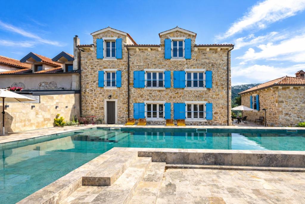 a villa with a swimming pool in front of a building at Deluxe Nature Resort Galovi Dvori in Rab