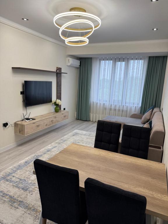 a living room with a table and a couch and a television at ЖК Сити Парк in Osh