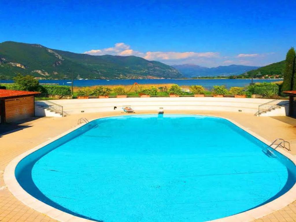 a large swimming pool with a view of a lake at Respiro di Lago - Pool Friend in Paratico