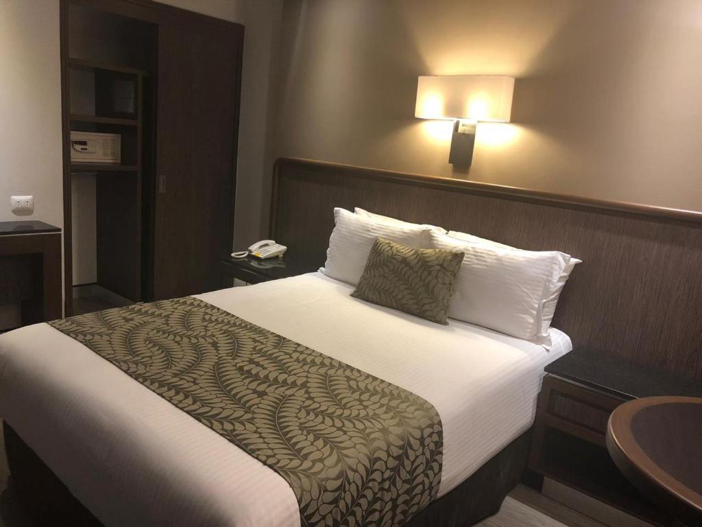 A double room showing a bed, bedside table, open shelving, and a wall-mounted lamp.