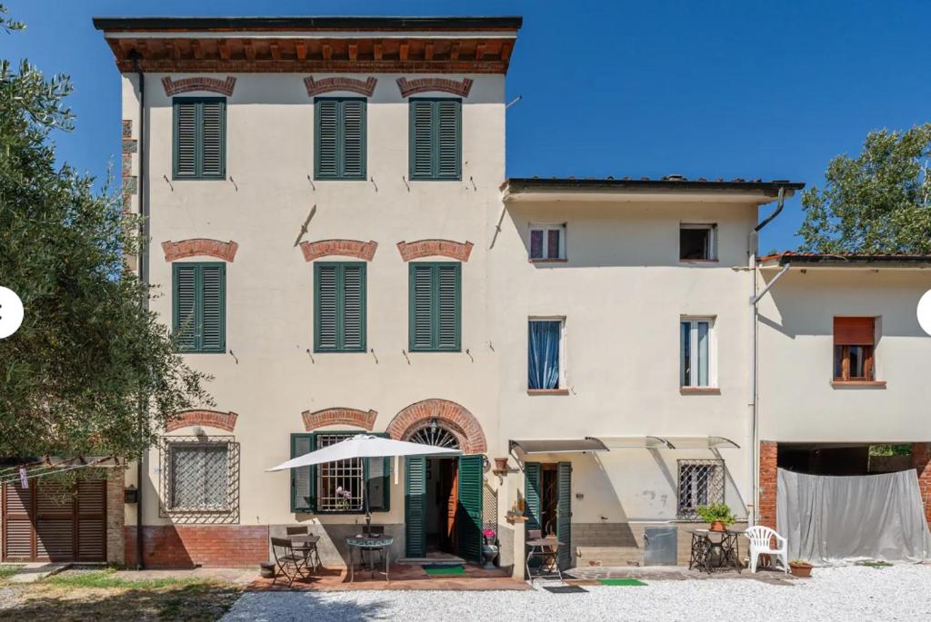 a large white building with green shuttered windows at Charming LUCCA in Lucca