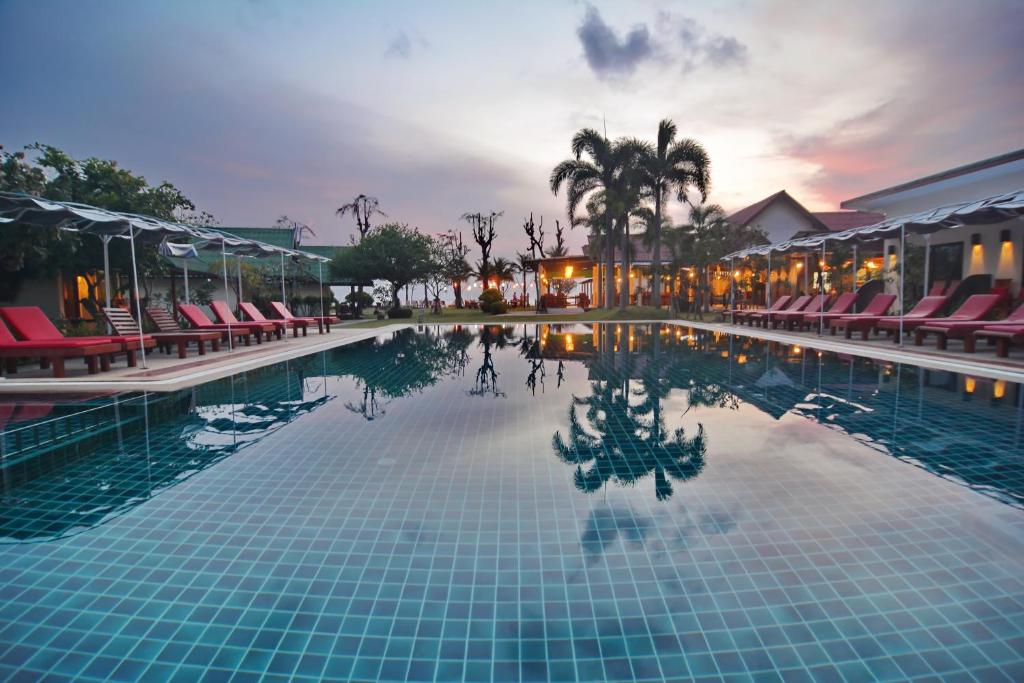 una piscina in un resort con sedie e un tramonto di Golden Bay Cottage - SHA Extra Plus a Ko Lanta