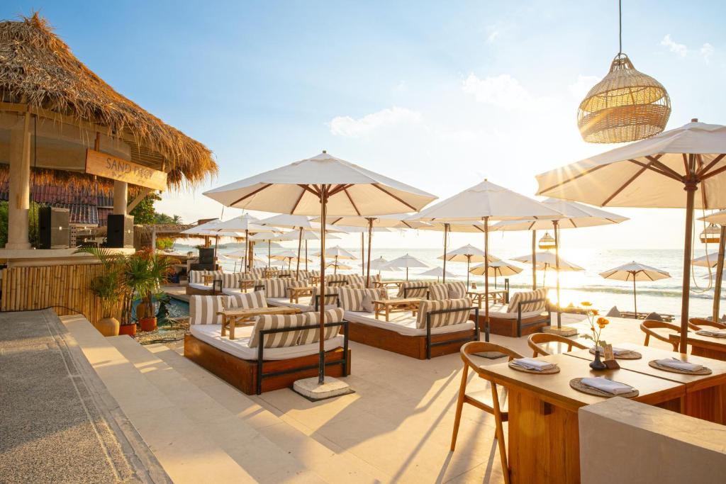 a patio with chairs and umbrellas on the beach at The Beachfront Hostel in Chaweng