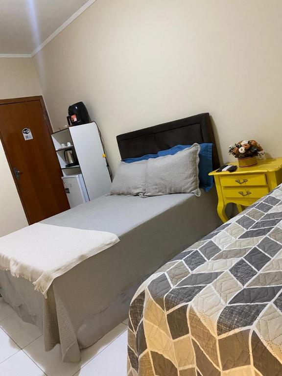 a bedroom with two beds and a yellow dresser with a night stand at Chick Nina Loft in Barra do Garças