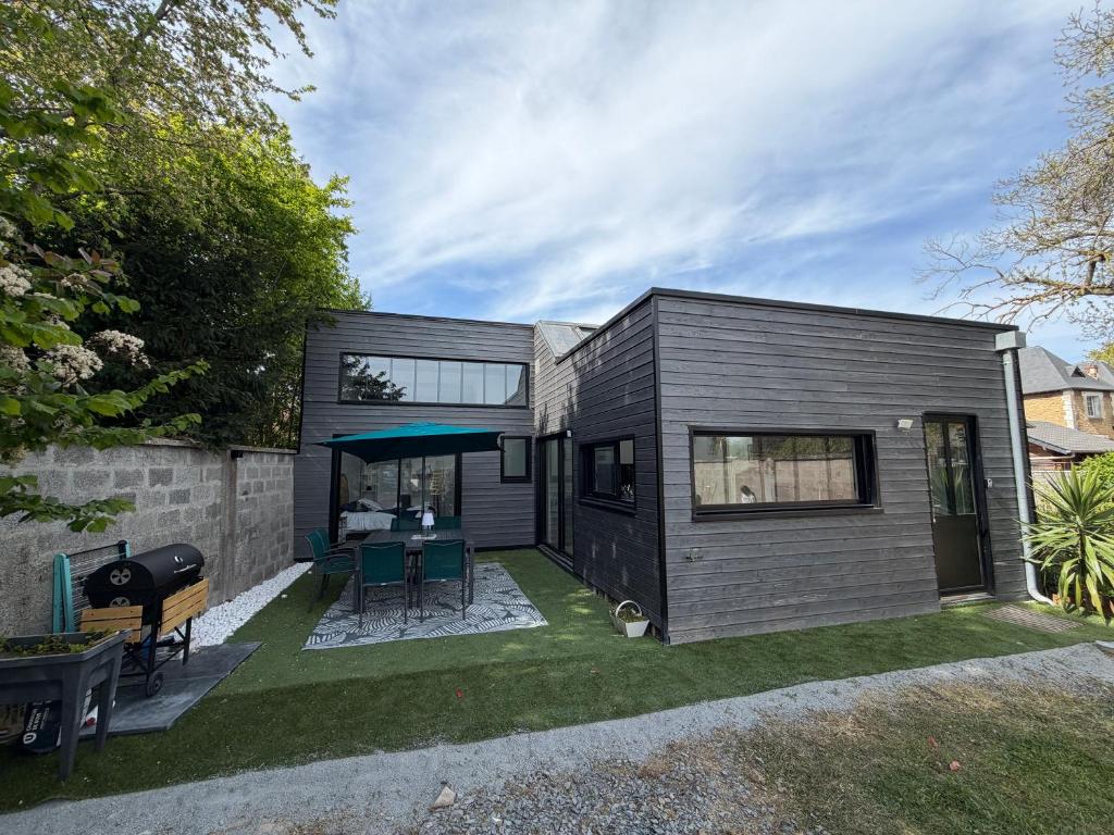 a small black tiny house with a backyard at Le rivage 44 in Bénouville