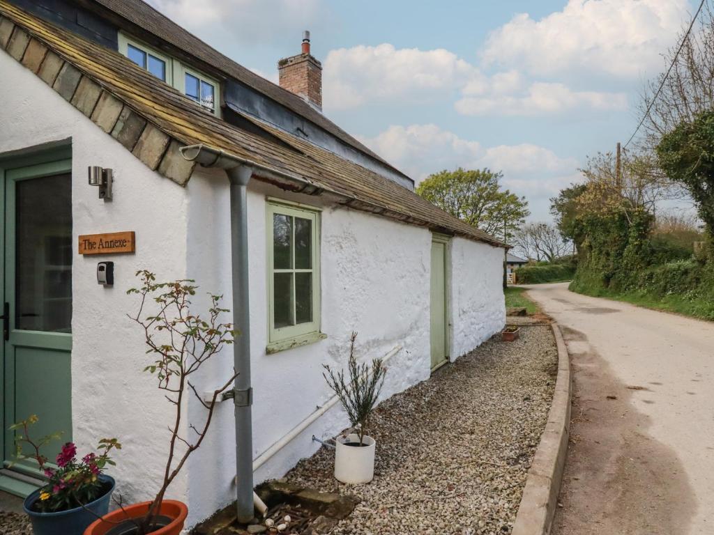 a white cottage with a green door and a road at Trevarthian Farm Annex in Newquay