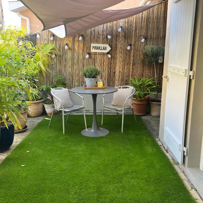 a patio with a table and chairs on green grass at Maisonnette studio Arcachon 300m plage in Arcachon