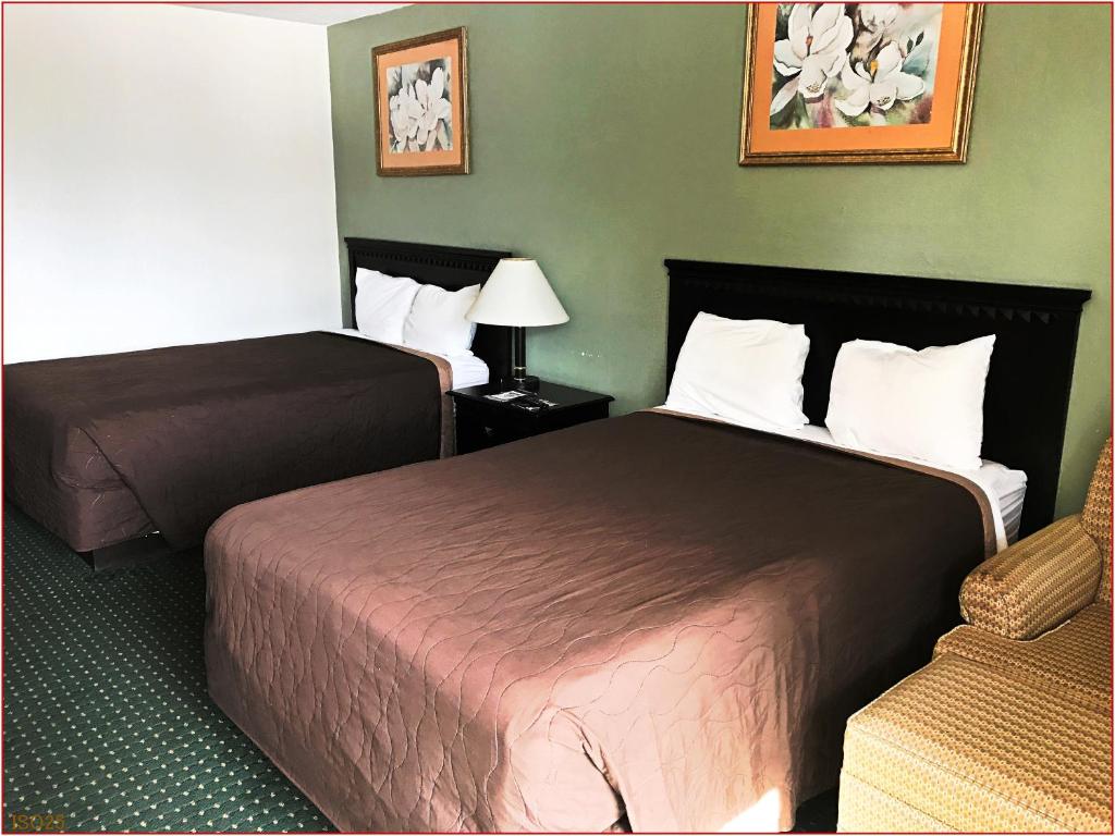 a hotel room with two beds and a chair at Stay Inn - Bartow in Bartow