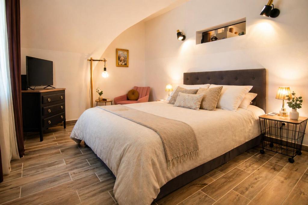 a bedroom with a large bed and a television at L'écrin du Pont du Gard - Parking gratuit - Charme & Pierres in Remoulins