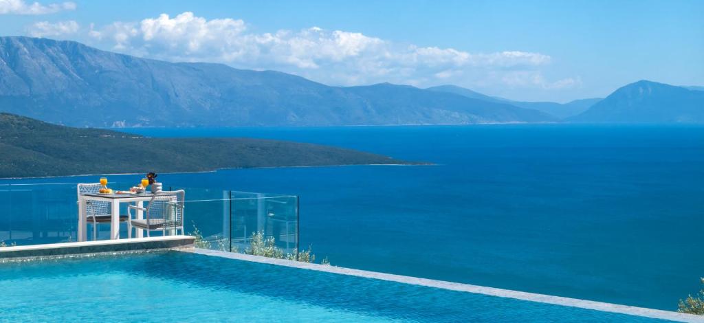 a person sitting on a table next to the water at Grey Sea View Estate - Luxury Villas with Private Pool & Plunge Pool in Katouna