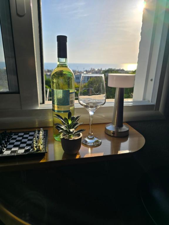 a bottle of wine and a glass on a table with a window at Elias Apartment in Kissonerga