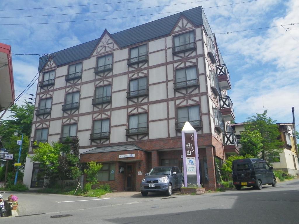 a large building with a car parked in front of it at Resort Inn Murata in Iiyama