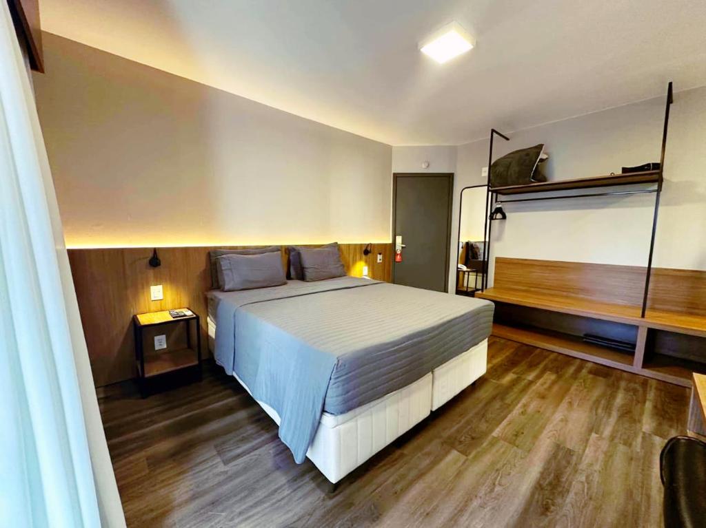 a bedroom with a large white bed and wooden floors at Flat Executive City Jardins in São Paulo