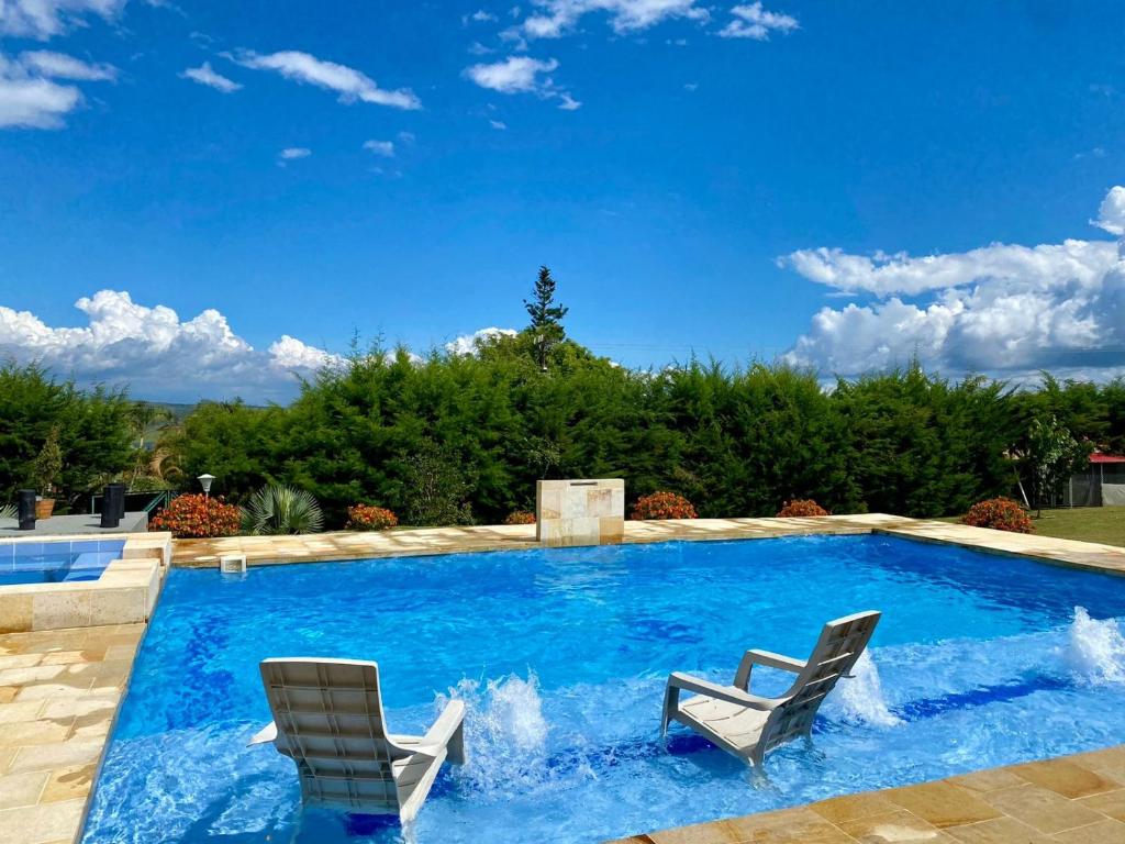 a swimming pool with two chairs and a swimming pool at Finca Campestre en el Lago Calima "Doña Ime" in Calimita