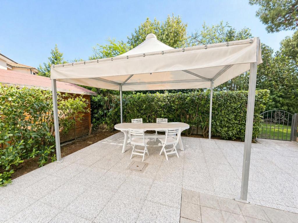 a white umbrella on a patio with a table and chairs at Dimora Scacciapensieri a Marina di Cecina by Zoom In Earth in Marina di Cecina