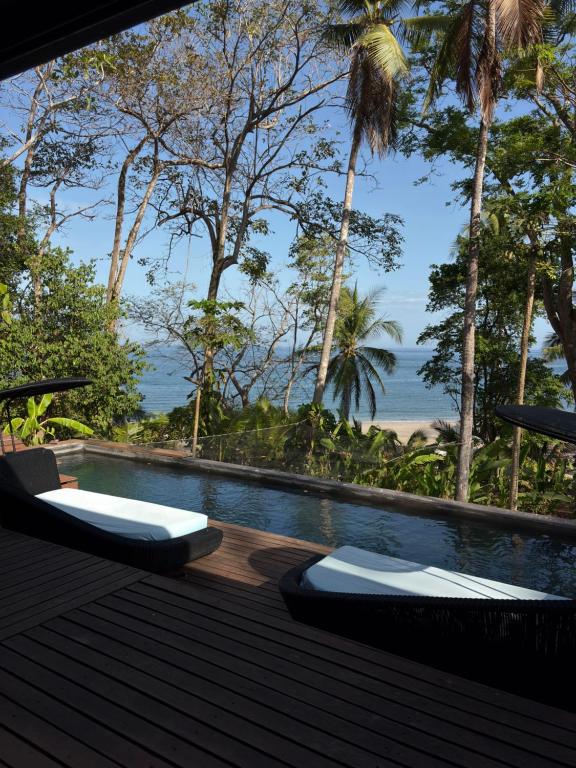 a swimming pool with two lounge chairs and the ocean at La Laguna in Saboga