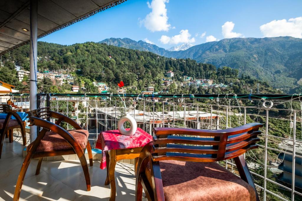 a balcony with chairs and a table with a view at Art-llers Homestay in Dharmsāla