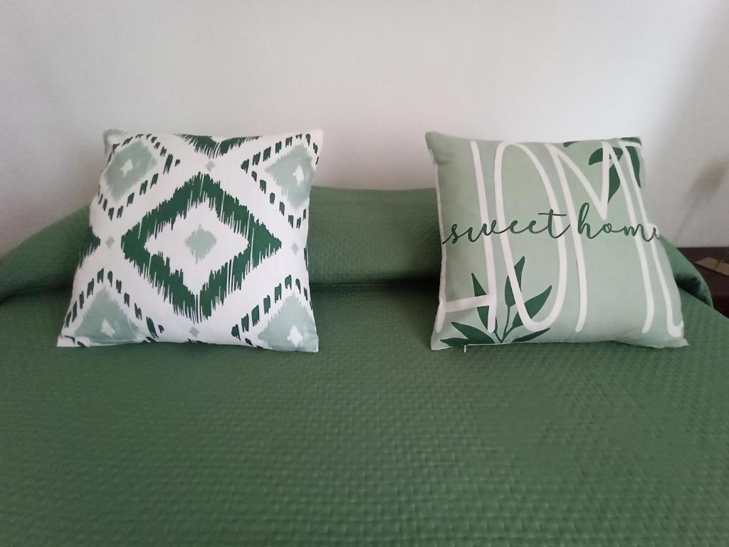 two pillows sitting on a bed with green sheets at Marisella holidays house in Pozzuoli