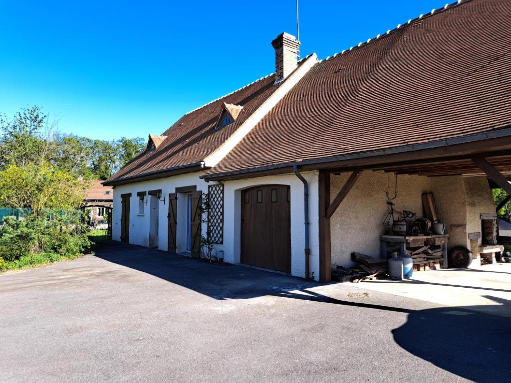 a house with a garage with a roof at Escapade bucolique calme et nature in Saint-Léger-aux-Bois