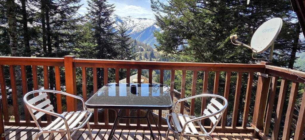 a table and chairs on a deck with a snow covered mountain at Chalet Fontaine 54 in Ustou