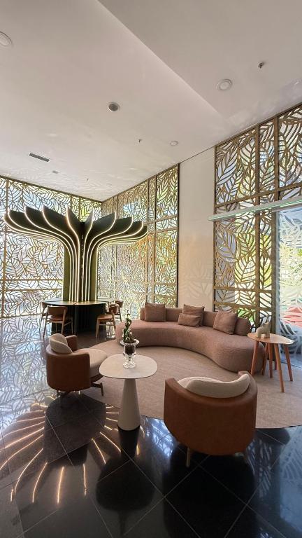 a living room with a couch and chairs and a tree at Flat de Luxo no Quality Hotel no coração de Alphaville in Barueri