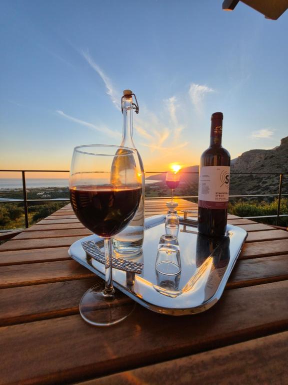 a glass of wine and a bottle on a table with the sunset at Casa di Olive Luxury Secluded Sea View Villa in South Crete in Goúdhouros
