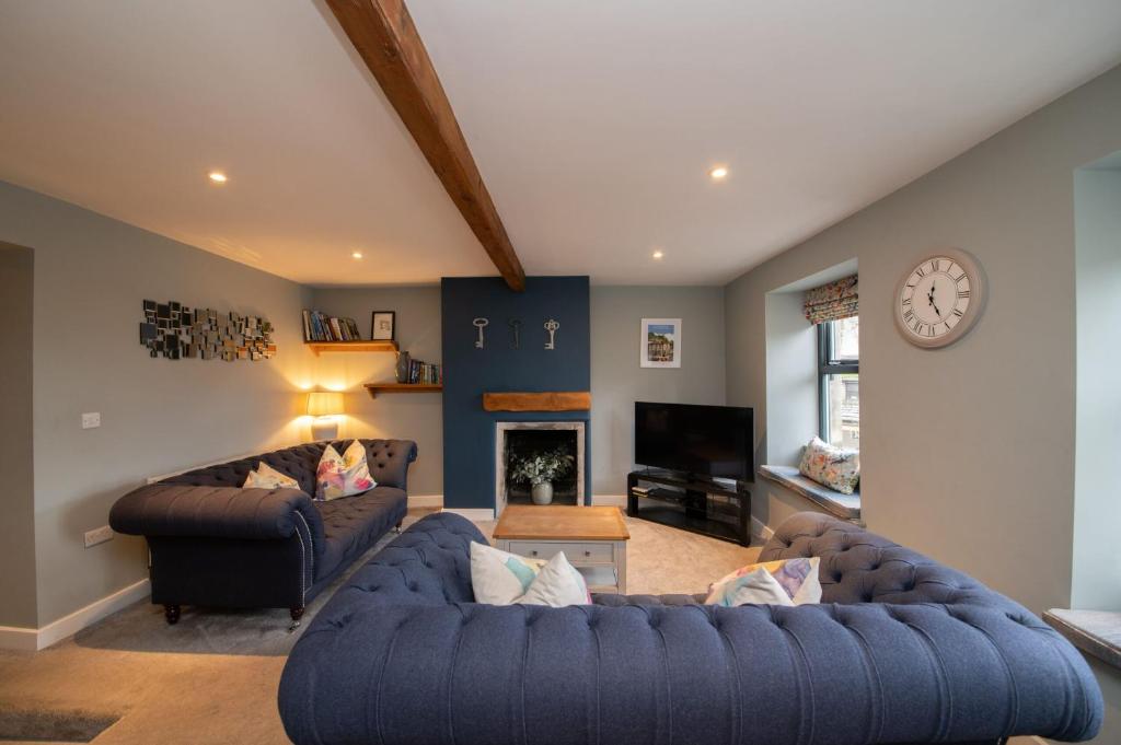 a living room with two couches and a clock at The Lookout Holmfirth in Holmfirth