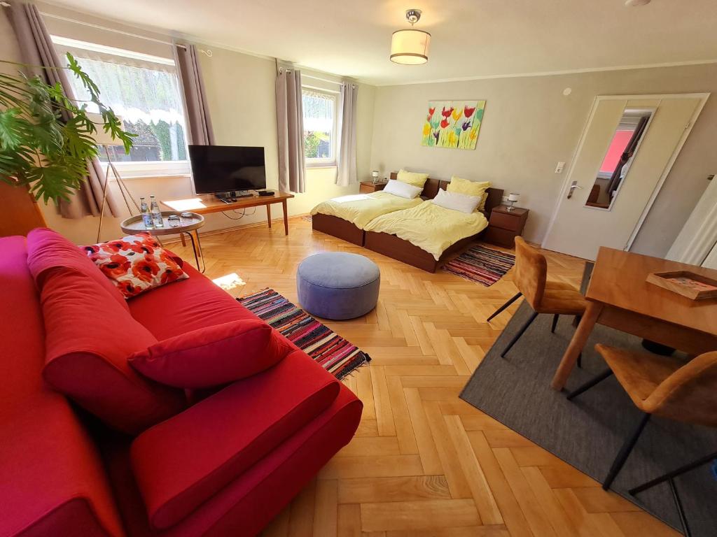 a living room with a red couch and a table at Gästehaus Mohr in Eberhardzell