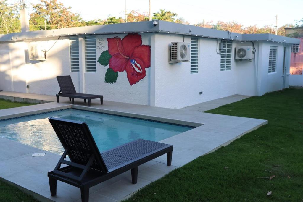 a swimming pool with two chairs next to a house at The Mango House in Fajardo