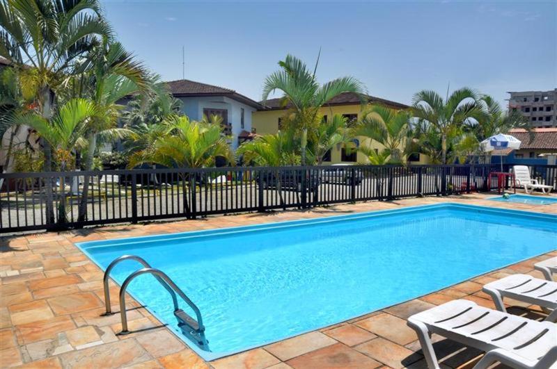 a large swimming pool with chairs and a fence at Associação Sabesp Bertioga - SP in Bertioga
