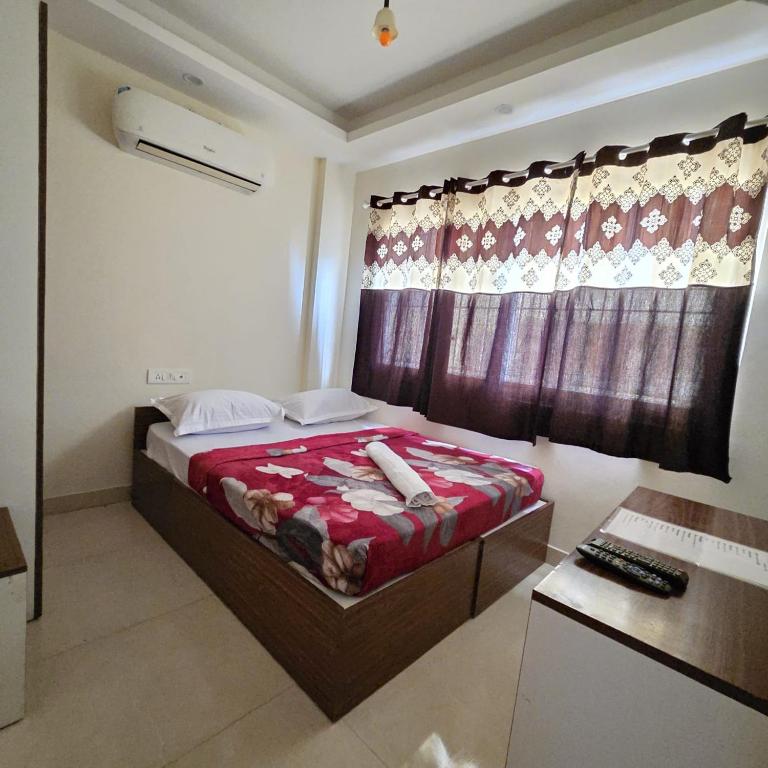 a bedroom with a bed with a red blanket and a window at Sumithra Palace in Bangalore