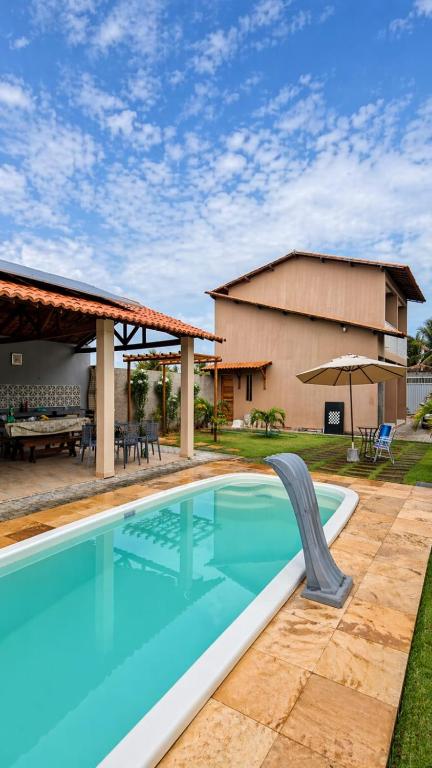 a swimming pool with a patio and a house at Pousada VillageMar in Cascavel