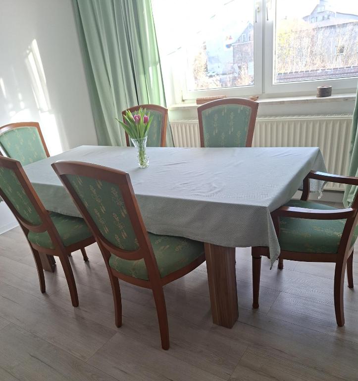 a table with chairs and a vase of flowers on it at Ferienwohnung Egbert in Weißwasser