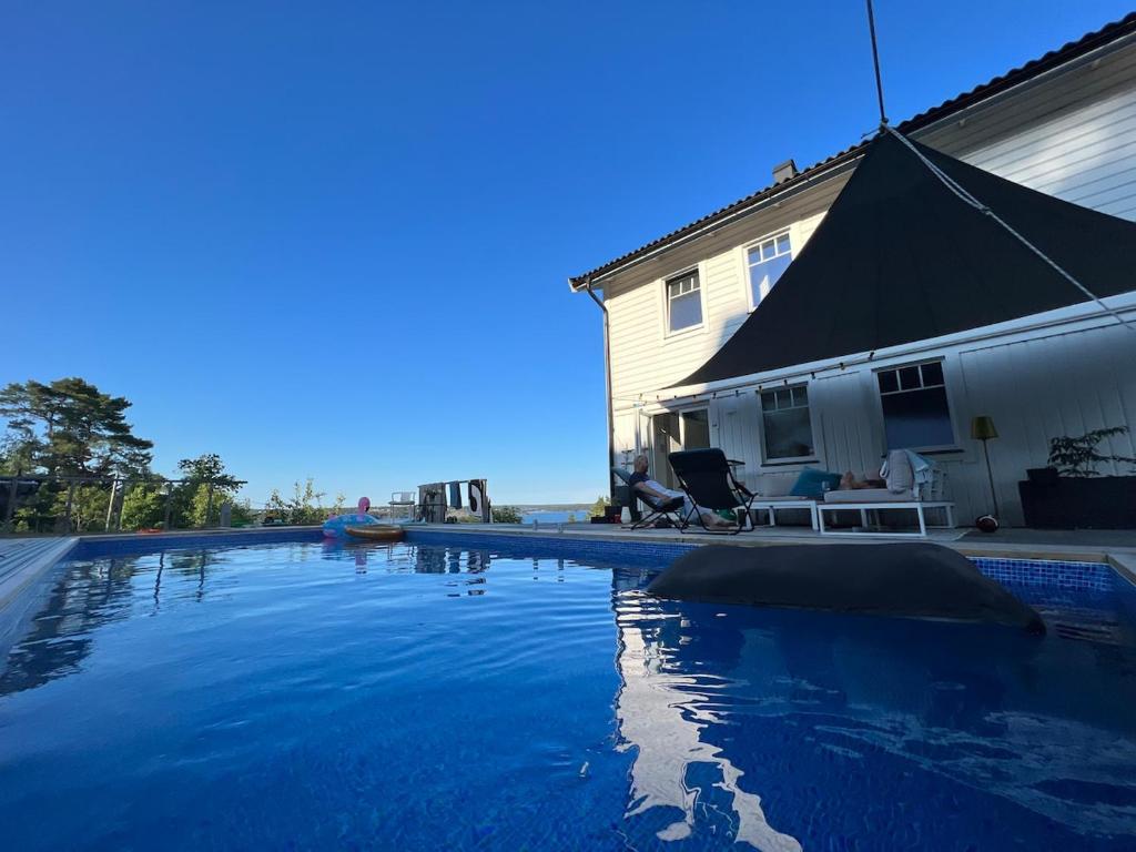 a swimming pool in front of a house at Beautiful pool villa with stunning ocean view in Tyresö