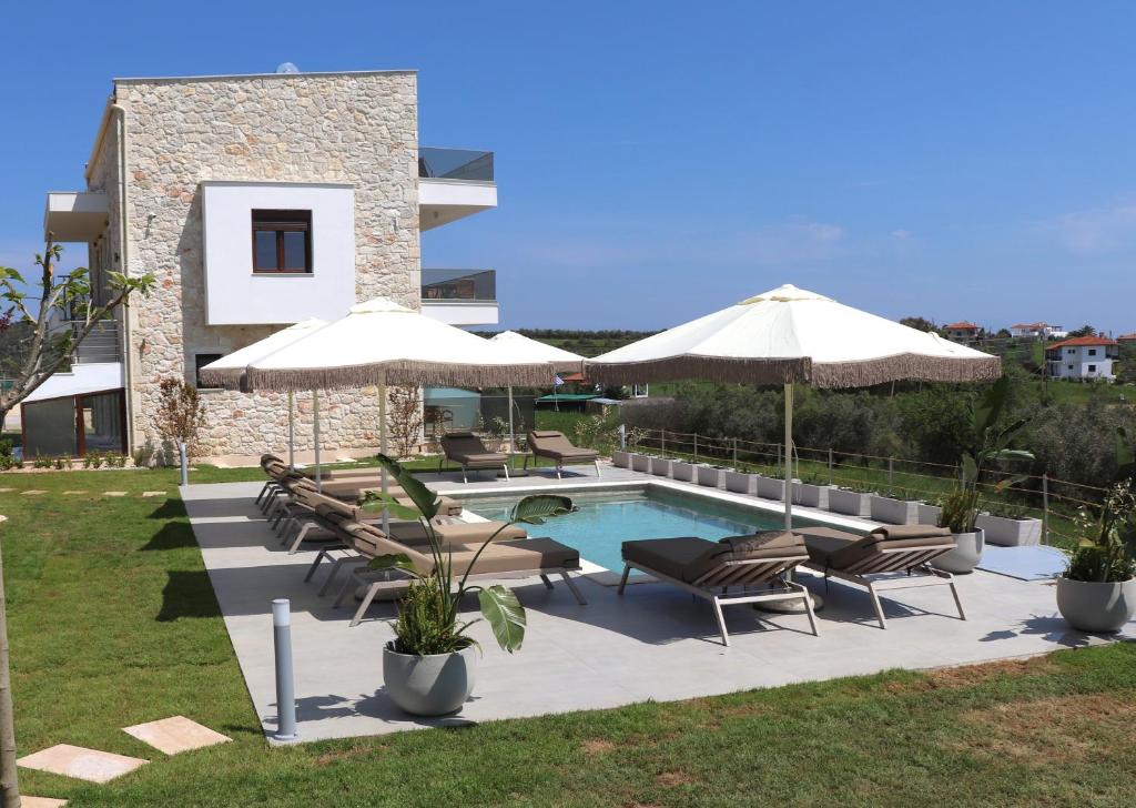 a patio with chairs and umbrellas and a swimming pool at Aria Vista Chalkidiki in Agios Nikolaos