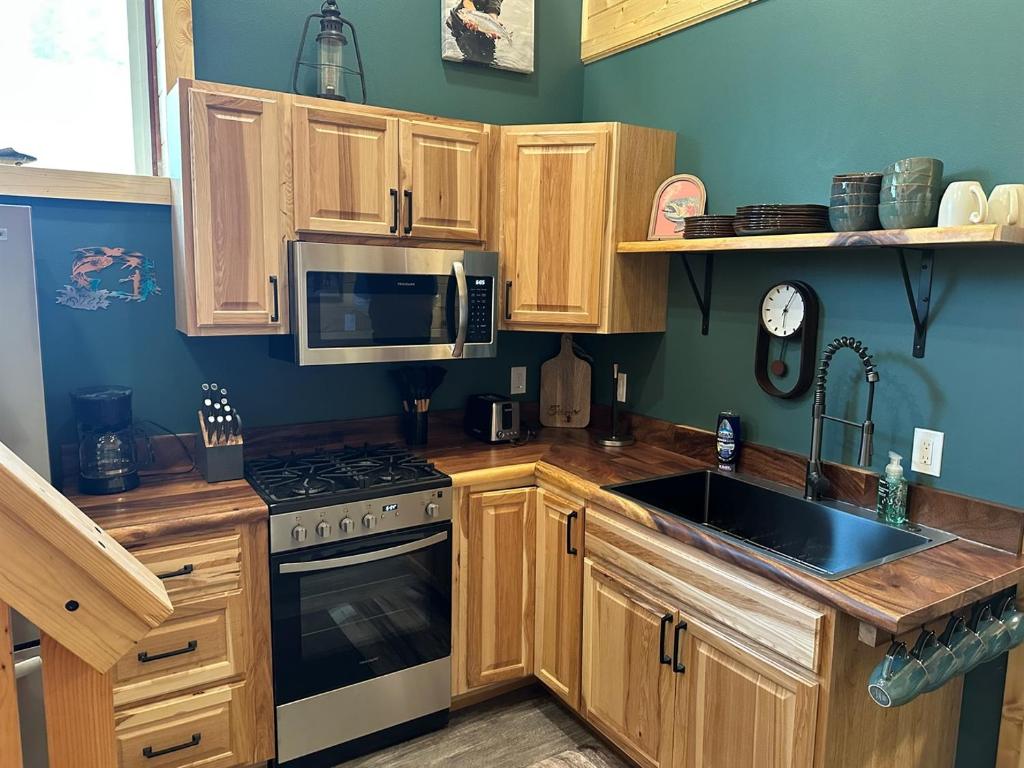 a kitchen with wooden cabinets and a stove and a sink at Catch'em AK - Trout Haven in Soldotna
