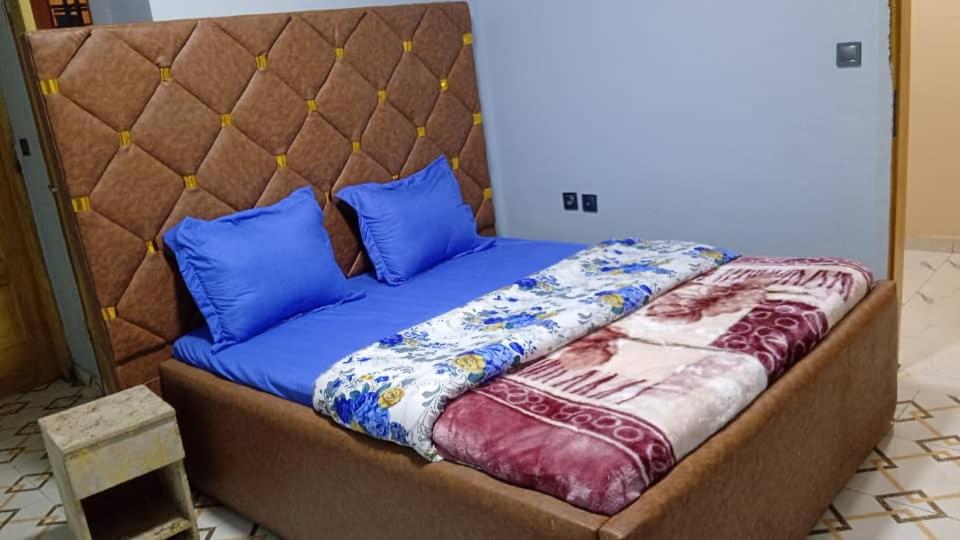 a bed with blue and purple pillows on it at SKY BLUE guest house in Buea