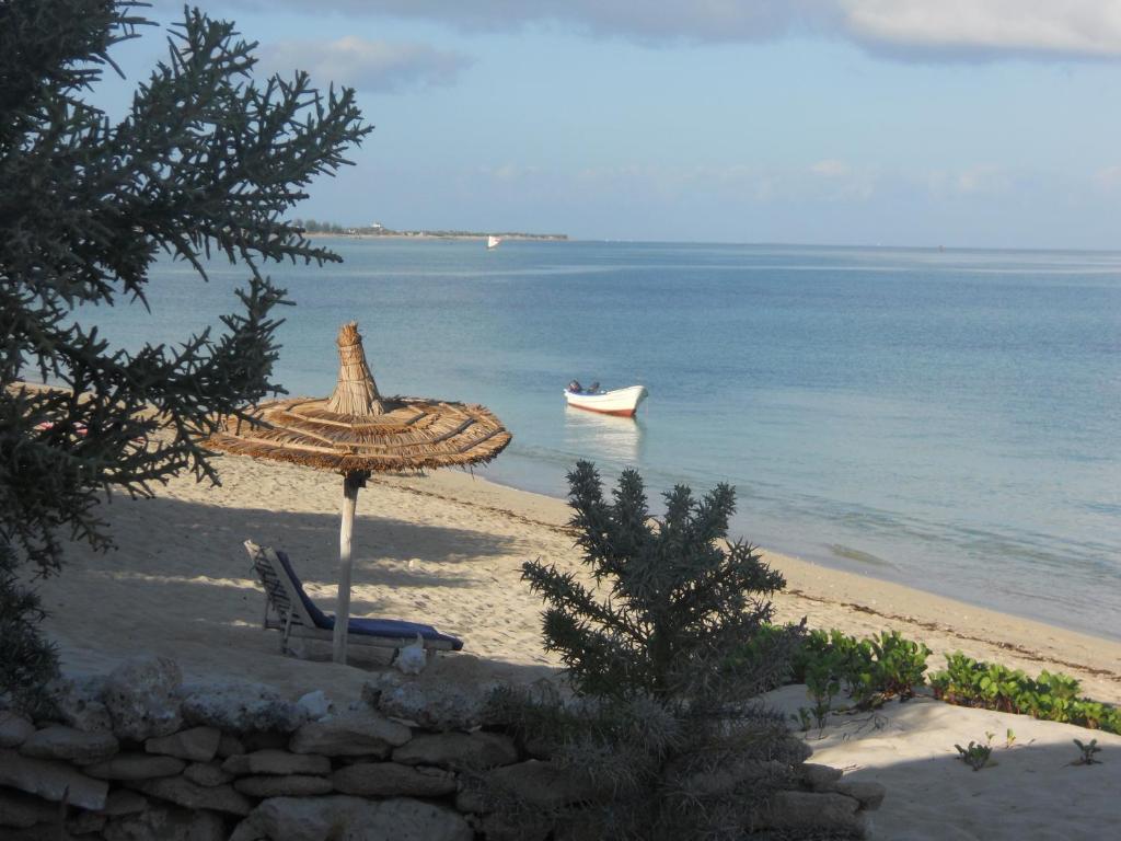 Longo Vezo في Anakao: شاطئ فيه مظله وقارب في الماء