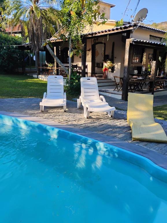 two chairs and a swimming pool in front of a house at Pousada bella mar buzios in Búzios