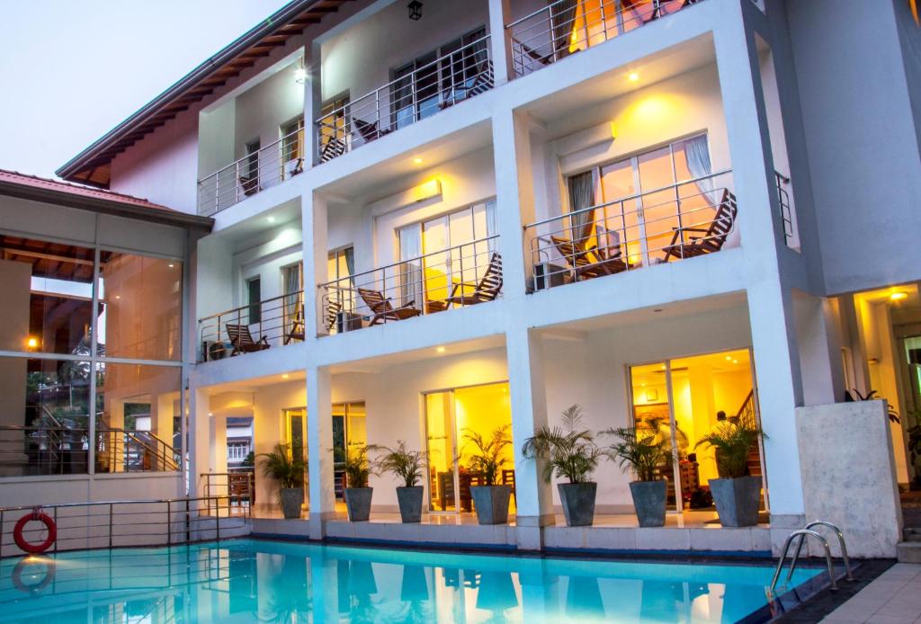 un hotel con piscina frente a un edificio en Senani Hotel, en Kandy