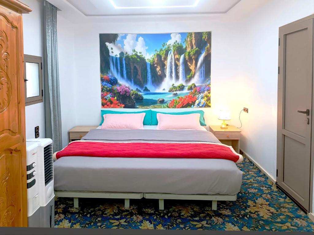 a bedroom with a bed with a painting on the wall at Aziz House 1 Tan Tan in Tan-Tan