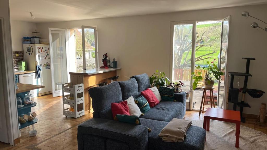 a living room with a blue couch with colorful pillows at L'Ombre du pommier in Paron