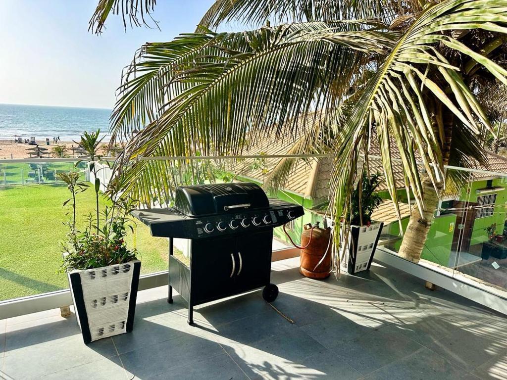 a grill on a patio with a palm tree and the ocean at Luxurious Orchid Apartment in Bijilo