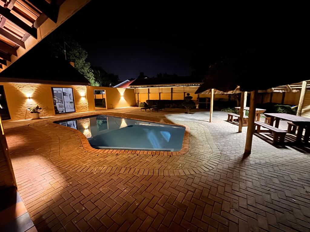 a swimming pool at night with a table and an umbrella at Golf View Guest House in Mahikeng