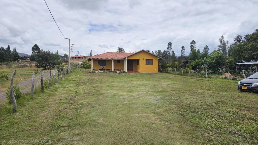 a yellow house in the middle of a field at Cabaña Santa Alicia in Villa de Leyva