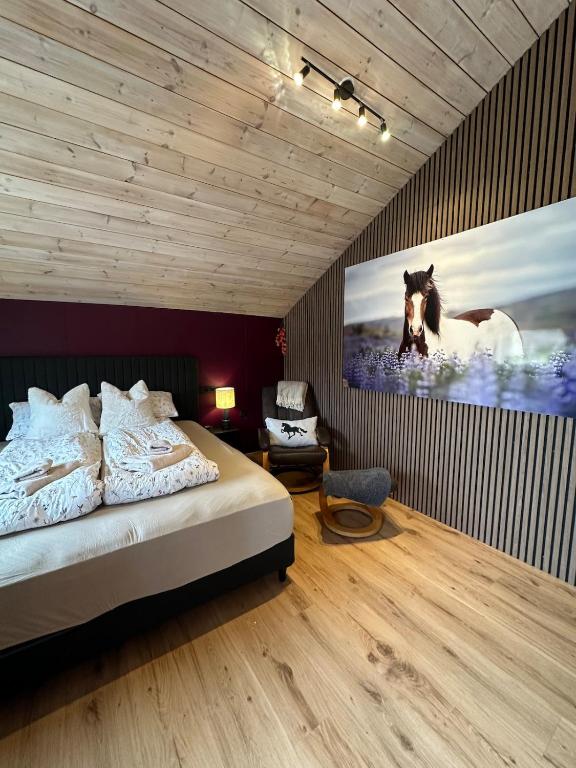 a bedroom with a bed and a painting of a horse at Hoofprints Farm stay in Fludir