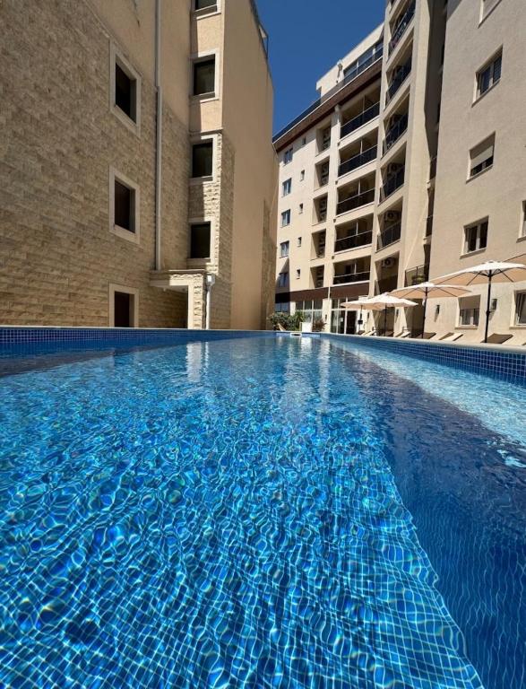 a large swimming pool in a building with two buildings at Becici Chic 1BR Condo swimming pool long term in Budva